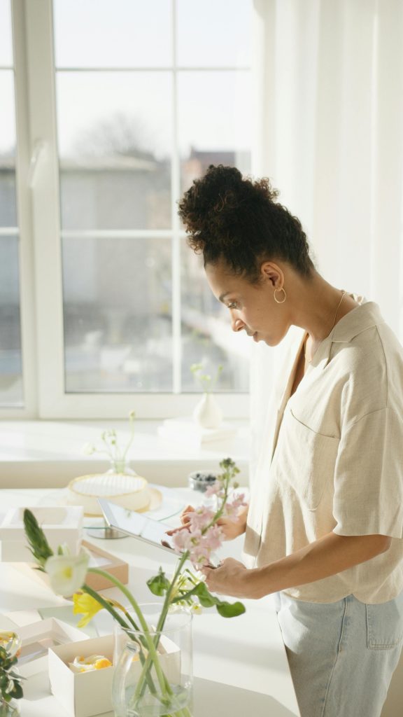 A young woman enjoys a peaceful moment arranging flowers in a bright room.